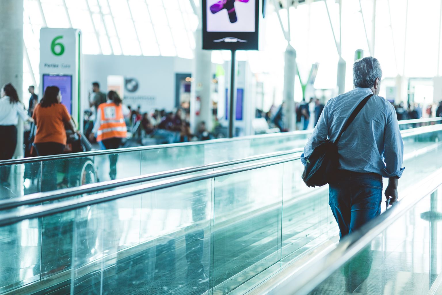 Businessman riding a moving walkway through a busy airport terminal